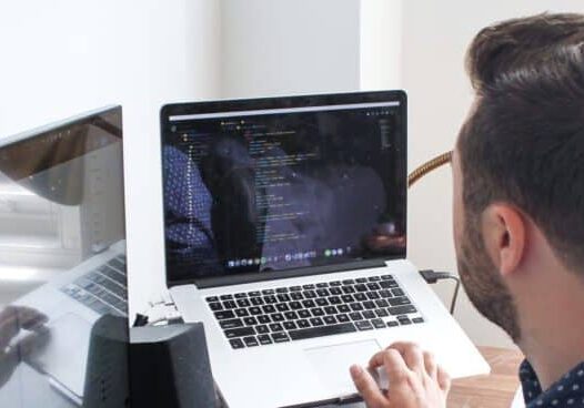 Over-the-shoulder view of man working on laptop