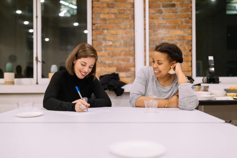 Two women working together at a large conference room table