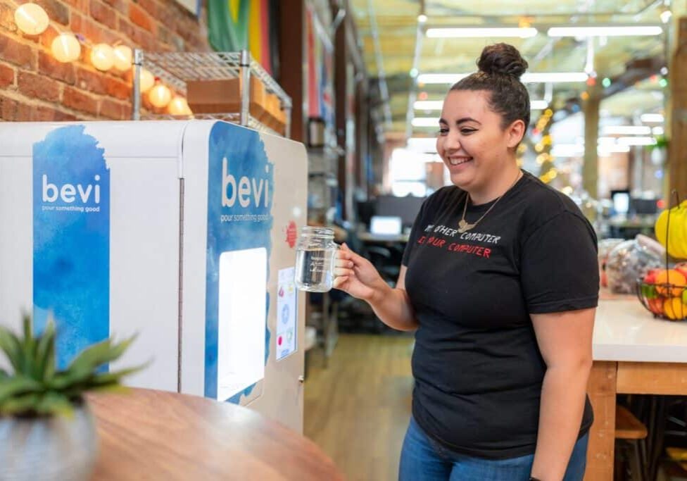 Young woman with hair in a bun getting water from a Bevi machine
