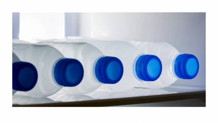 Row of plastic water bottles on their sides on a refrigerator shelf