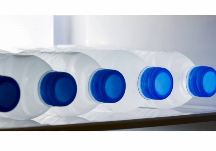 Row of plastic water bottles on their sides on a refrigerator shelf