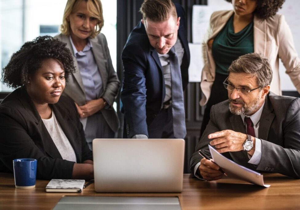 Four office workers gathered around a laptop computer