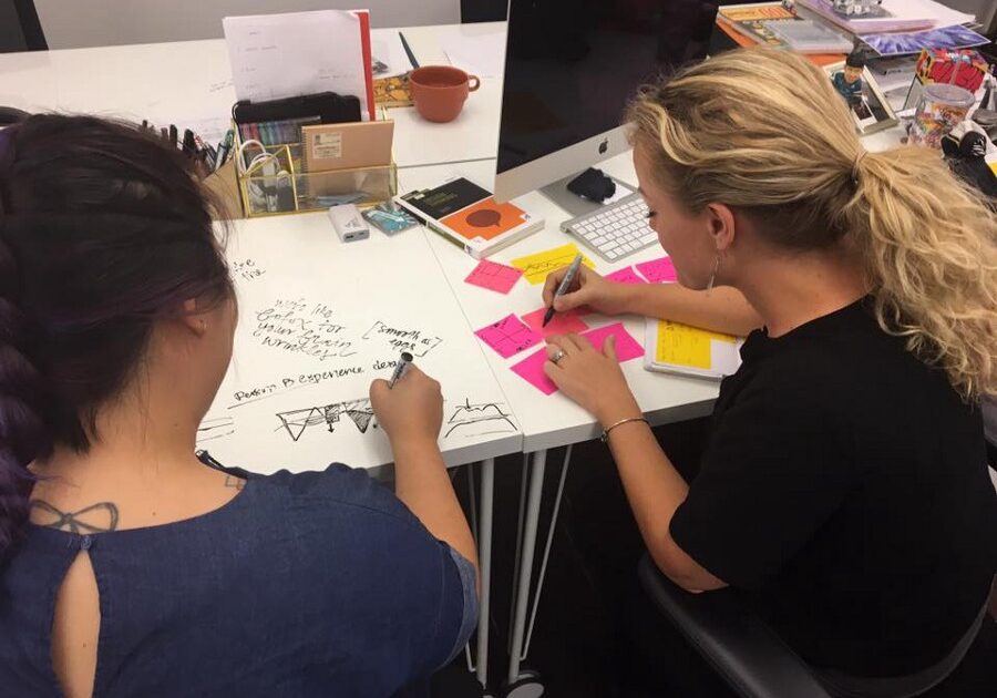 Two women working side by side at a large office table