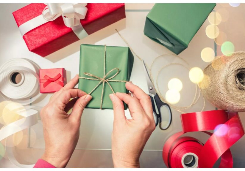 Overhead view of two hands wrapping a gift