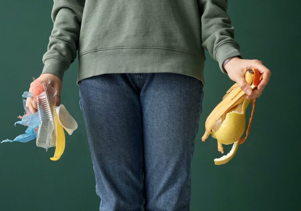A person holding organic food waste in one hand and plastic waste in another