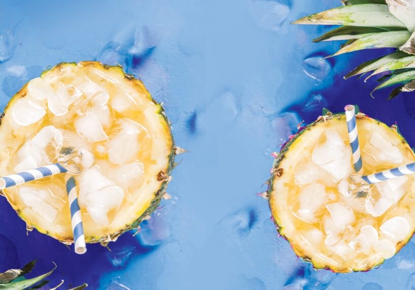 Two pineapple halves with a drinking straw in each