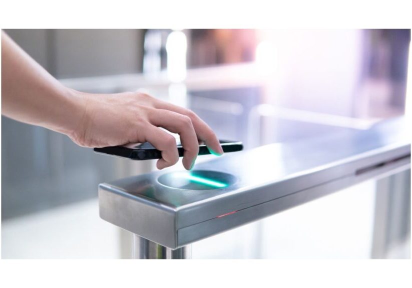 Hand holding mobile phone over an access control device