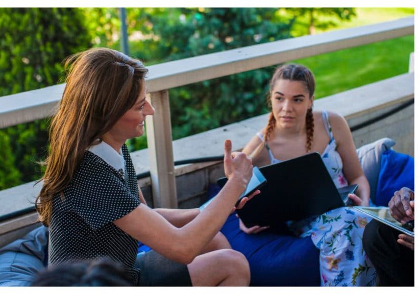 Two women taling while sitting outside on a deck