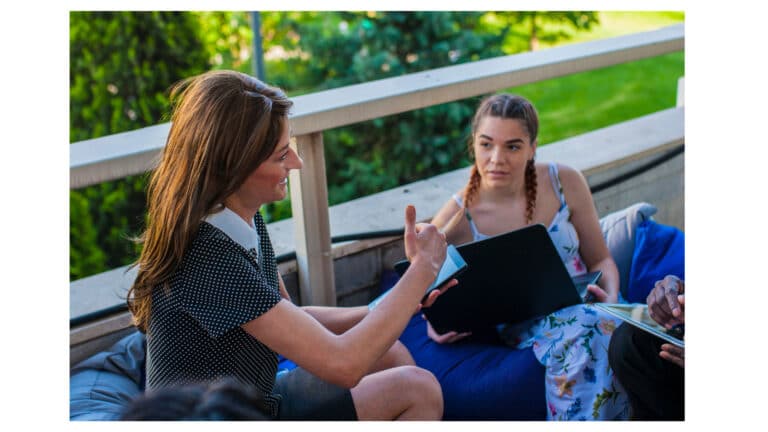 Two women taling while sitting outside on a deck